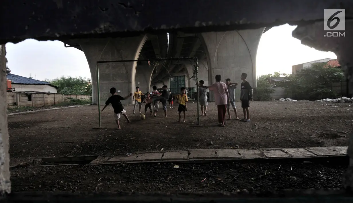 Anak-anak bermain sepak bola di kolong jalan Tol Lingkar Utara, Kalibaru, Cilincing, Jakarta, Kamis (28/3). Lahan di kolong jalan tol tersebut rencananya oleh Pemkot Jakarta Utara akan disulap menjadi ruang terbuka hijau bernama Taman Maju Bersama (TMB). (merdeka.com/Iqbal S Nugroho)