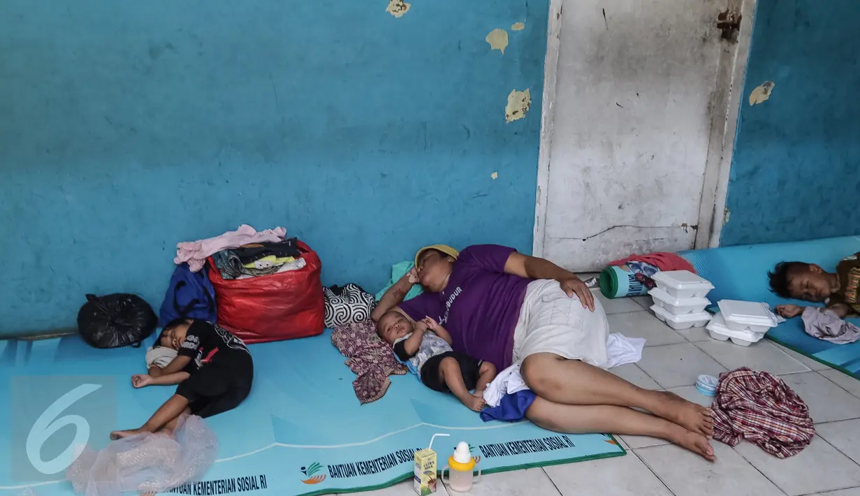 Seorang ibu dan putranya tengah tertidur di depan kelas Sekolah Dasar Kristen, Fajar Sion, Jakarta Barat, Minggu (8/1). Mereka sudah mengungsi di sekolah tersebut selama 3 hari karena rumahnya terbakar pada Kamis lalu. (Liputan6.com/Fery Pradolo)