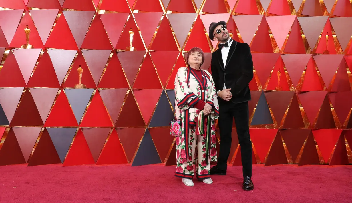 Agnes Varda dan JR menghadiri malam penghargaan Piala Oscar 2018 atau Academy Award ke-90 di Los Angeles, Minggu (4/3). Agnes Varda memilih mengenakan sepatu warna perak ketimbang hak tinggi di karpet merah. (Neilson Barnard/GETTY IMAGES/AFP)