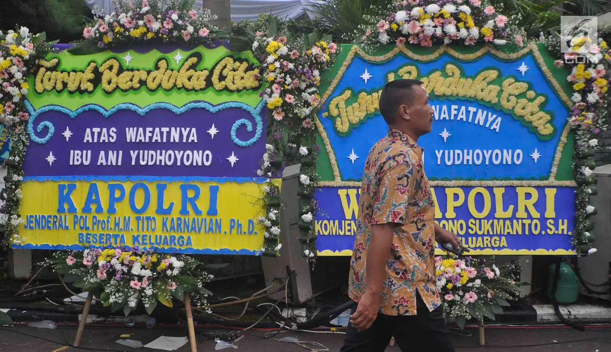 Seorang pria berjalan melewati karangan bunga ucapan bela sungkawa wafatnya Ani Yudhoyono menghiasi kawasan Puri Cikeas, Bogor, Jawa Barat, Minggu (2/6/2019). Ani Yudhoyono akan dimakamkan di samping pusara istri presiden ke-3 RI BJ Habibie, Ainun. (Liputan6.com/Immanuel Antonius)