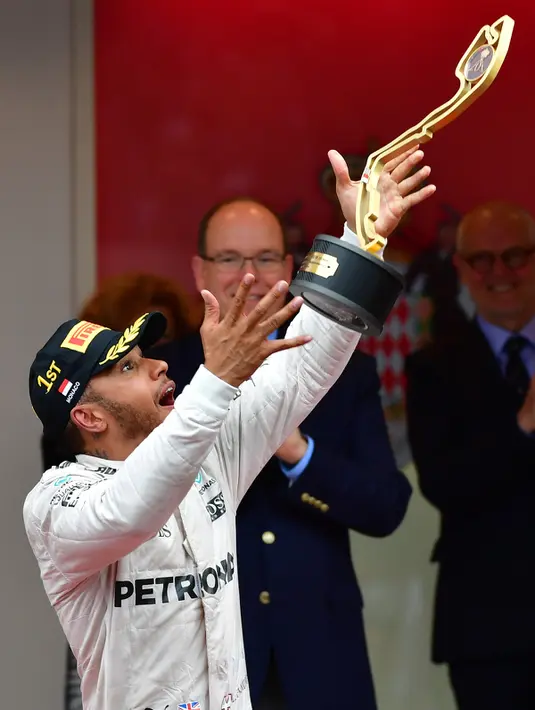 Pembalap Lewis Hamilton melemparkan piala saat melakukan selebrasi usai berhasil menjuarai Grand Prix di Monaco, (29/5). Hamilton menjadi yang tercepat dengan mencatatkan waktu satu jam 59 menit 29,133 detik. (AFP PHOTO/ANDREJ ISAKOVIC)