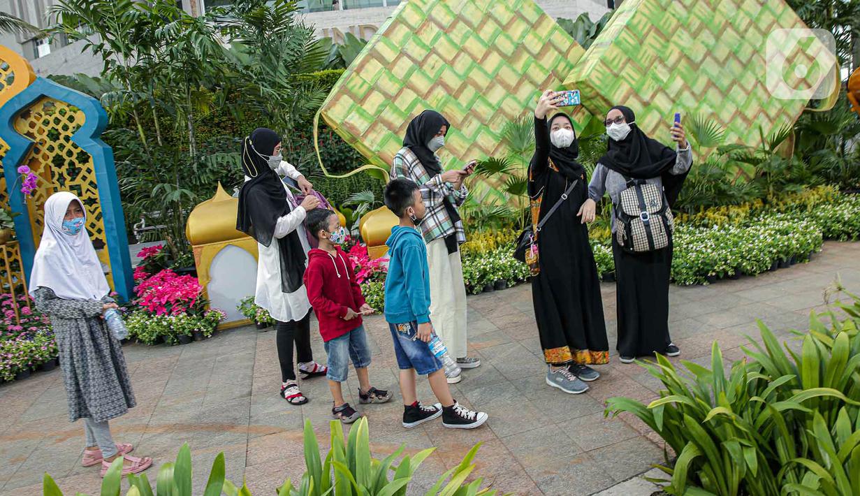 <p>Sejumlah warga berfoto dengan dekorasi bertemakan Idul Fitri di kawasan Bundaran HI, Jakarta, Rabu (27/4/2022). Dekorasi berbentuk masjid, ketupat, dan bedug yang dihiasi oleh tanaman tersebut dalam rangka menyambut Idul Fitri 1443 Hijriah. (Liputan6.com/Faizal Fanani)</p>