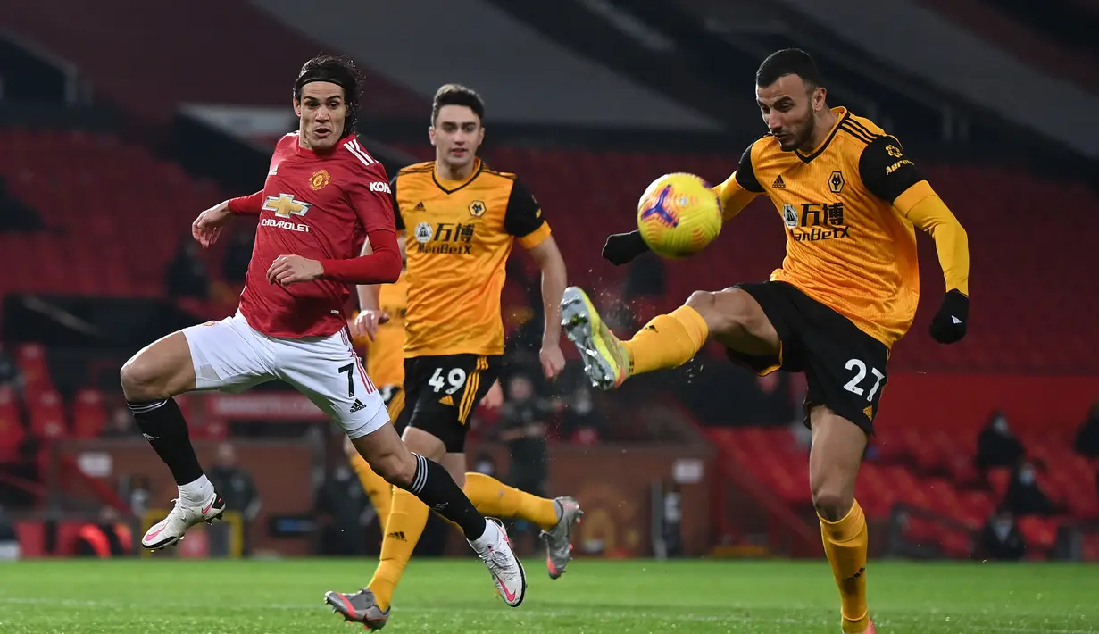 Gelandang Wolverhampton Wanderers, Romain Saiss (kanan) menguasai bola di depan striker Manchester United, Edinson Cavani dalam laga lanjutan Liga Inggris 2020/21 pekan ke-16 di Old Trafford, Selasa (29/12/2020). Wolverhampton kalah 0-1 dari Manchester United. (AFP/Laurence Griffiths/Pool)