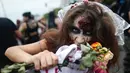 Seorang wanita memakai kostum dan dandanan menyerupai zombie dalam acara Zombie Walk di pantai Copacabana, Rio de Janeiro, Brasil, Jumat (2/11). Ribuan orang ini beraksi sebagai Zombie untuk memeriahkan peringatan Hari Para Arwah. (Mauro PIMENTEL/AFP)