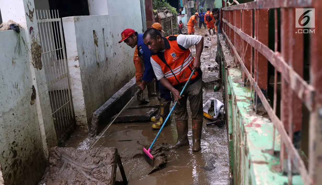 Petugas Damkar PB bersama PPSU membersihkan lumpur sisa banjir di salah satu gang di kawasan Rawajati, Jakarta, Sabtu (27/4). Banjir akibat luapan air sungai Ciliwung sempat melanda kawasan ini pada Jumat (26/4). (Liputan6.com/Helmi Fithriansyah)