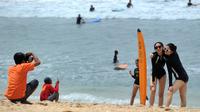 Dua turis wanita berpose saat difoto di pantai Kuta di pulau pariwisata Indonesia di Bali (4/1). Daerah ini merupakan tujuan wisata turis mancanegara dan telah menjadi objek wisata andalan Pulau Bali sejak awal tahun 1970-an. (AFP Photo/Sony Tunbelaka)
