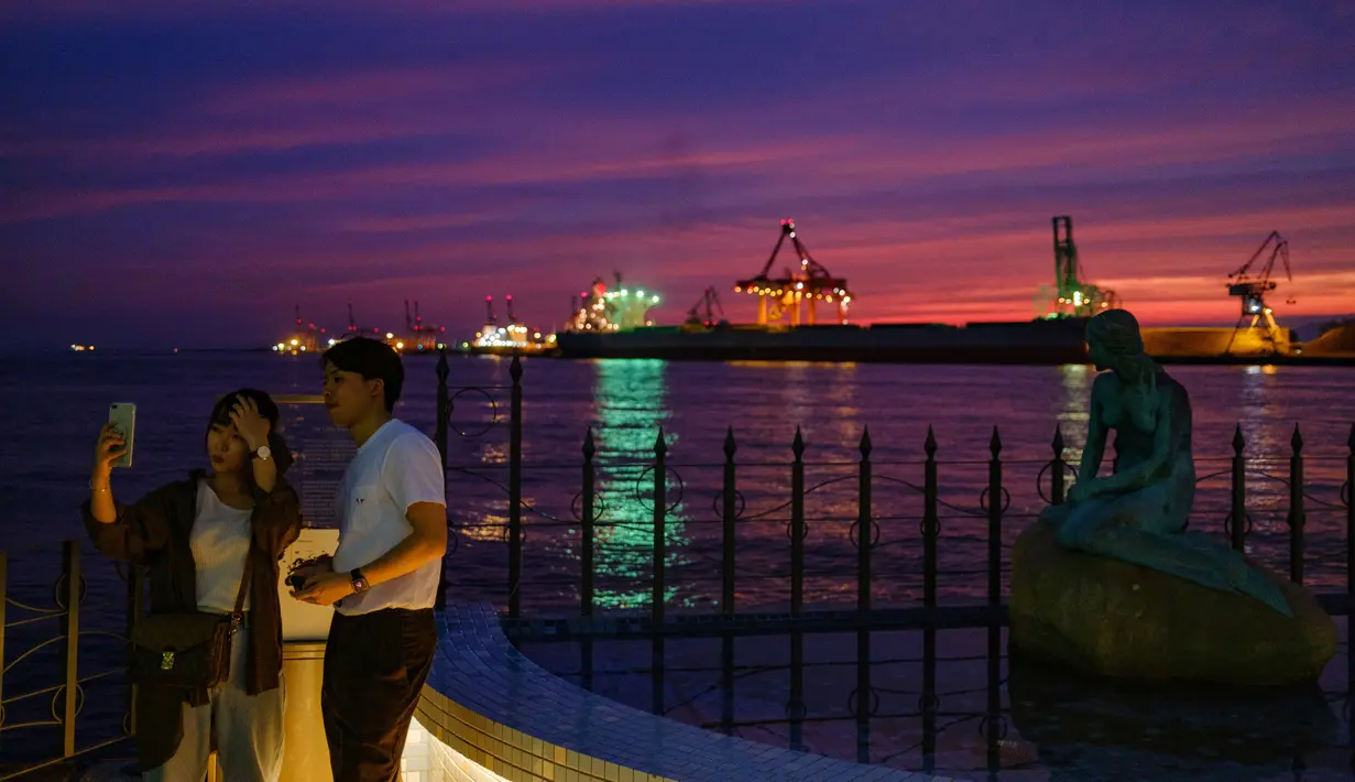 Pasangan yang sedang berpose untuk berfoto di kawasan pejalan kaki pelabuhan di Osaka (20/9/2020). Pelabuhan Osaka adalah salah satu pelabuhan utama di Jepang, berlokasi di Teluk Osaka. (AFP/Philip Fong)