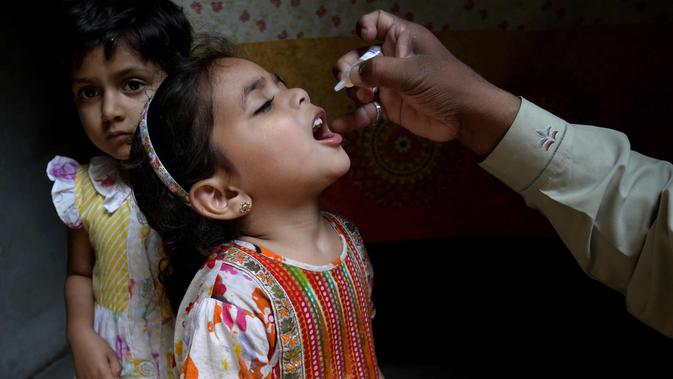 Seorang anak msaat diberikan vaksin polio oleh pekerja kesehatan di Lahore, Pakistan, (9/4). Pakistan meluncurkan vaksinasi polio baru, yang bertujuan agar 38,7 juta anak di bawah usia 5 tahun mendapatkan vaksin tersebut. (AP Photo/KM Chaudary)