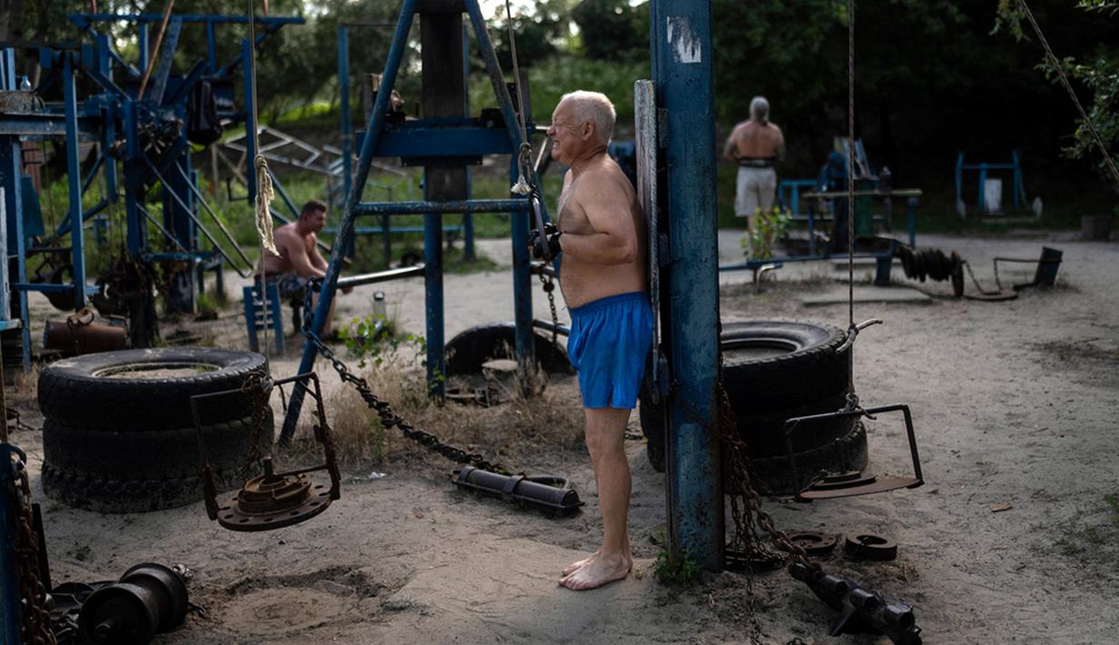 Seorang pria berolahraga menggunakan peralatan yang terbuat dari besi bekas di gym luar ruangan Kachalka, Kiev, Ukraina, Rabu (12/7/2023). Gym luar ruangan yang dibuka sejak tahun 1966 ini terletak di Pulau Dolobetskyi, Ibu Kota Ukraina. (AP Photo/Jae C. Hong)
