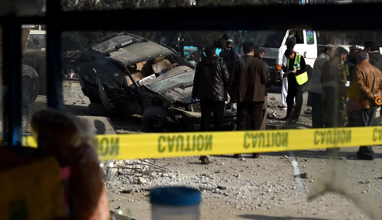 Anggota keamanan Afghanistan memeriksa sebuah mobil yang rusak akibat ledakan bom di jalanan Ibu Kota Afghanistan, Kabul, Rabu (28/12). Kendaraan yang ditumpangi anggota parlemen bernama Fakori Behishti hancur akibat ledakan ini. (WAKIL KOHSAR/AFP)