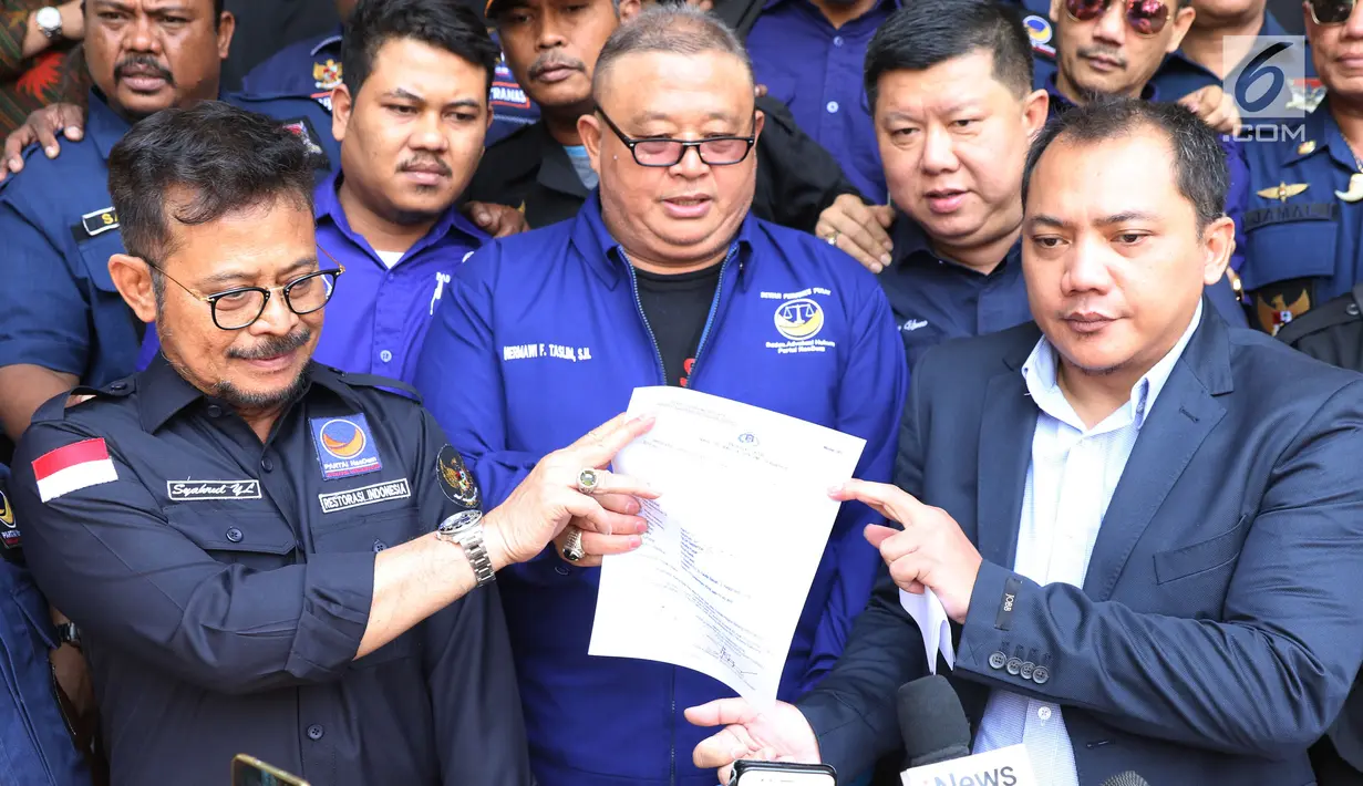 Kuasa Hukum Partai Nasdem, Herman Taslim (tengah) menunjukkan surat tanda bukti lapor di Polda Metro Jaya, Senin (17/9). Partai Nasdem melaporkan Rizal Ramli atas dugaan pencemaran nama baik dan fitnah. (Liputan6.com/Helmi Fithriansyah)