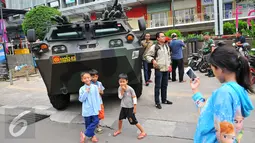 Anak-anak berpose di depan panser Anoa milik TNI di LTC Glodok, Jakarta, Jumat (4/11). Pengamanan tersebut untuk mengantisipasi jika terjadi kerusuhan terkait demo bela islam yang sedang berlangsung. (Liputan6.com/Angga Yuniar)