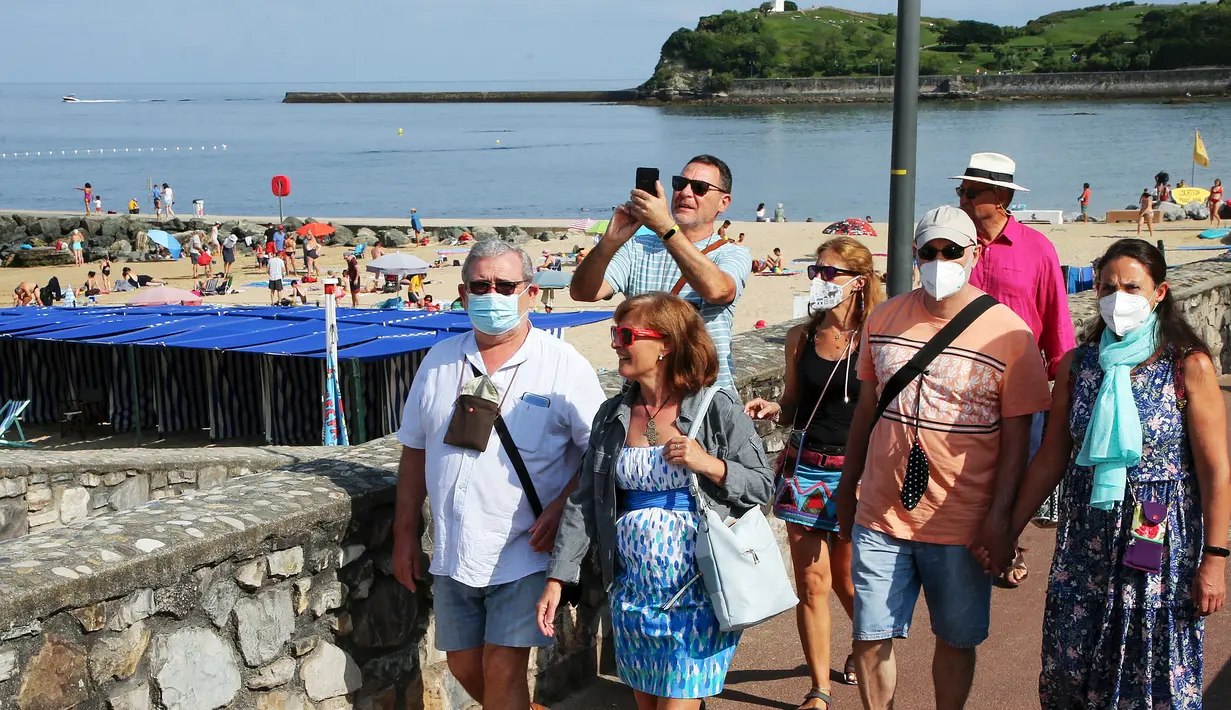 Orang-orang memakai masker berjalan di sepanjang pantai di Saint Jean de Luz, Prancis barat daya, Selasa (27/7/2021). Otoritas setempat di Prancis memberlakukan kembali mandat masker dan pembatasan COVID-19 lainnya karena penyebaran varian delta menyebabkan rawat inap meningkat lagi. (AP/Bob Edme)