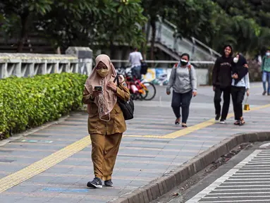 Sejumlah pekerja berjalan usai bekerja di Jalan Jenderal Sudirman, Jakarta, Selasa (10/5/2022). Pemerintah mengimbau masyarakat menerapkan bekerja dari rumah atau work from home (WFH) selama satu hingga dua pekan ke depan untuk mengantisipasi penyebaran virus corona COVID-19 usai libur Lebaran 2022. (Liputan6.com/Faizal Fanani)