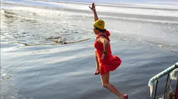 Seorang wanita melompat untuk berenang di danau  yang sebagaian beku dengan es saat suhu minus 20 derajat Celcius di Shenyang di provinsi Liaoning timur laut China (10/12). (AFP Photo/Str/China Out)
