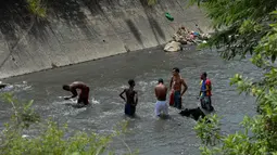 Sejumlah pria mencari logam berharga di Sungai Guaire, di Caracas, Venezuela (1/2). Puluhan warga mencari logam atau tembaga setiap hari di Sungai Guaire, tempat selokan Caracas mengalir.  (AFP Photo/Federico Parra)