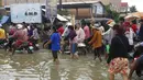 Pekerja garmen pergi ke tempat kerja melalui jalan yang banjir setelah hujan di  Phnom Penh, Kamboja (14 /10/2020). Pejabat bencana Kamboja mengatakan bahwa lebih dari 10.000 orang telah dievakuasi ke tempat aman setelah badai tropis melanda yang menyebabkan banjir bandang.  (AP Photo/Heng Sinith)