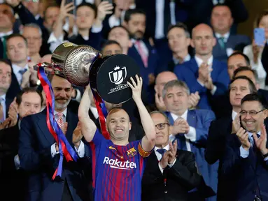 Kapten Barcelona, Andres Iniesta mengangkat trofi Copa del Rey setelah memenangkan pertandingan melawan Sevilla pada babak final di stadion Wanda Metropolitano di Madrid, Spanyol (21/4). Barcelona menang telak 5-0. (AP Photo / Paul White)