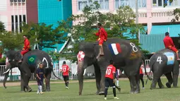 Tim Ayutthaya Wittayalai School bertanding sepakbola melawan gajah di sebuah sekolah di Provinsi Ayutthaya, Thailand, Selasa (12/6). Pertandingan digelar sebagai kampanye untuk mempromosikan Piala Dunia 2018. (AP Photo/Sakchai Lalit)