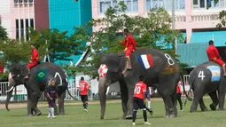 Tim Ayutthaya Wittayalai School bertanding sepakbola melawan gajah di sebuah sekolah di Provinsi Ayutthaya, Thailand, Selasa (12/6). Pertandingan digelar sebagai kampanye untuk mempromosikan Piala Dunia 2018. (AP Photo/Sakchai Lalit)