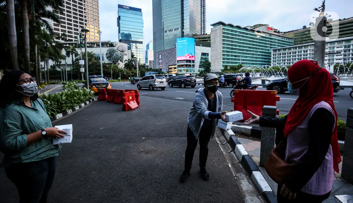 Suasana pembagian takjil kepada pejalan kaki di Kawasan Bundaran HI, Jakarta, Selasa (20/4/2021). Kegiatan berbagi takjil yang digagas oleh Pewarta Foto Indonesia Jakarta (PFIJ) ini dilaksanakan setiap hSelasa dan Jumat selama bulan Ramadhan sebagai bentuk solidaritas. (Liputan6.com/JohanTallo)
