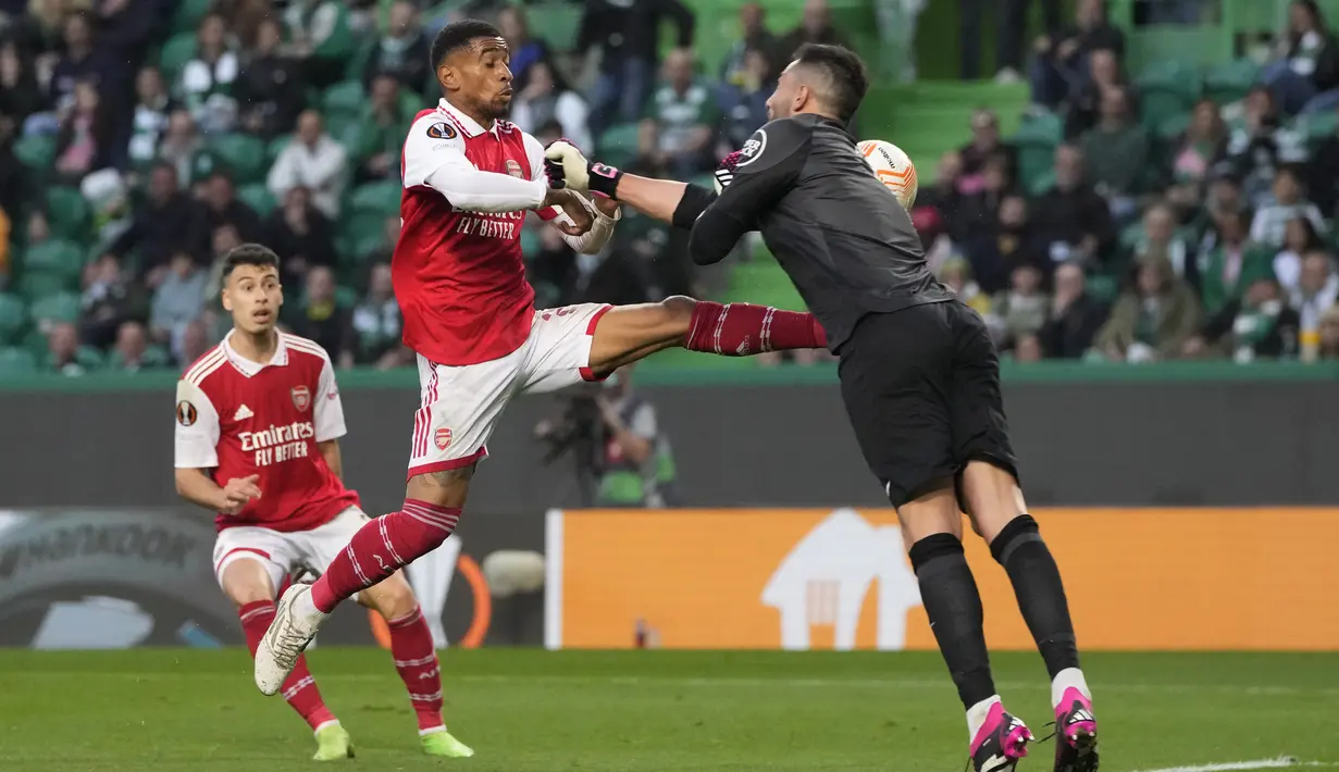 Penyerang Arsenal, Reiss Nelson menantang bola dengan kiper  Sporting CP, Antonio Adan dalam laga leg pertama babak 16 besar Liga Europa 2022-2023 di Estadio Jose Alvalade, Jumat (10/3/2023) dini hari WIB.  Arsenal dipaksa puas dengan hasil imbang 2-2 dalam lawatan ke markas Sporting Lisbon.  (AP Photo/Armando Franca)