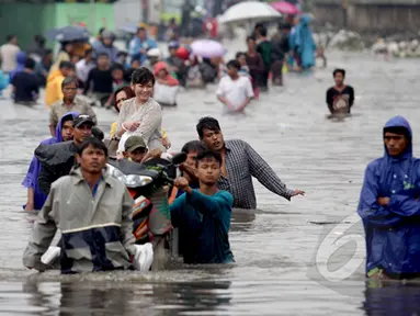 Sejumlah warga terpaksa menggunakan jasa gerobak untuk melintasi banjir yang setinggi dada orang dewasa di Jalan Gunung Sahari, Jakarta, Senin (6/2/2015). (Liputan6.com/Faizal Fanani)