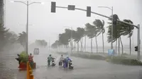 Pengendara motor menerjang hujan dan angin kencang yang dibawa Topan Mangkhut di Manila, Filipina (15/9). Topan Mangkhut menghantam pantai timur laut Filipina pada Sabtu pagi menghancurkan sebagian wilayah di negara tersebut. (AP Photo/Bullit Marquez)