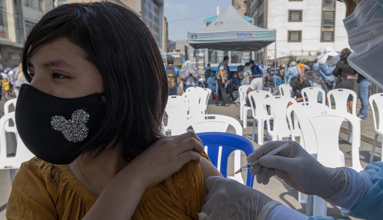 Seorang wanita disuntik vaksin COVID-19 Pfizer-BioNTech di pusat kesehatan darurat di jalan di pusat kota Lima,Rabu (5/1/2022). Peru melaporkan negara itu secara resmi menghadapi gelombang ketiga COVID-19 karena peningkatan kasus infeksi setelah perayaan Natal dan Tahun Baru. (Cris BOURONCLE/AFP)