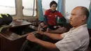 Pemain Mitra Kukar, Rizky Pellu duduk dekat nahkoda kapal feri saat berangkat latihan menyeberangi Sungai Mahakam menuju Stadion Aji Imbut, Tenggarong, Kaltim, Sabtu (3/10/2015). (Bola.com/Vitalis Yogi Trisna)