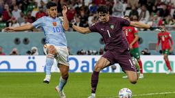 Pemain Spanyol, Marco Asensio (kiri) berusaha merebut bola dari&nbsp;kiper Maroko, Yassine Bounou saat laga 16 besar Piala Dunia 2022 yang berlangsung di Education City Stadium, Selasa (06/12/2022). (AP/Martin Meissner)