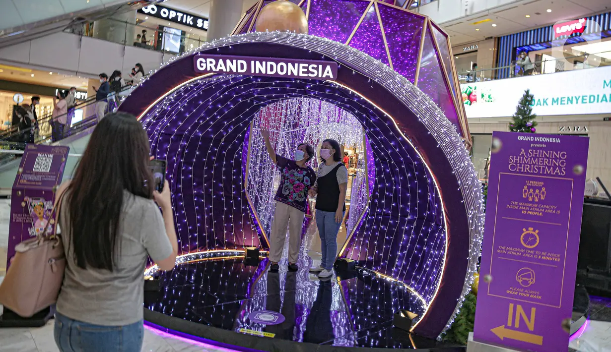 Pengunjung berswafoto di dekorasi perayaan Natal bertema "A Shining Shimmering Christmas" di Mal Grand Indonesia, Jakarta, Senin (13/12/2021). Pengunjung dapat menikmati kemegahan dan kehangatan Natal melalui dekorasi “infinity dome” yang berkilauan indah dan elegan. (Liputan6.com/Faizal Fanani)