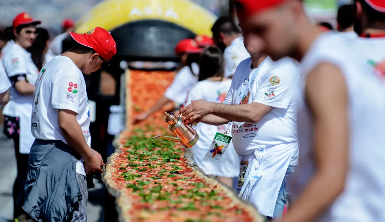 Sejumlah koki ahli berupaya mencetak rekor dunia dengan membuat pizza terpanjang di dunia, di sepanjang pinggir Laut Naples, Italia, 18 Mei 2016. Proses pembuatan pizza membutuhkan waktu sekira 11 jam dan 100 orang koki profesional. (Mario LAPORTA/AFP)