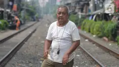 Penjaga perlintasan kereta api tanpa palang pintu, Wandi, menjaga perlintasan di Kawasan Petamburan, Jakarta, Jumat (4/6/2021). Sudah 10 tahun, Bapak Wandi menjaga palang pintu perlintasan kereta api yang kerap dilintasi oleh  pengguna jalan untuk menyeberang. (merdeka.com/Imam Buhori)