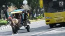 Delman hias membawa penumpang melintasi Jalan Medan Merdeka Selatan, Jakarta, Selasa (19/6). Masa libur Lebaran 2018 dimanfaatkan sejumlah warga untuk berwisata di sekitar Monumen Nasional dengan menaiki delman hias. (Liputan6.com/Helmi Fithriansyah)