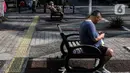 Seorang pria duduk sambil melihat ponsel di tengah Pemberlakuan pembatasan kegiatan masyarakat (PPKM) Level 4 di Jakarta, Minggu (1/8/2021). Sebelumnya bisa mencapai angka 350 - 400 kematian per hari. (Liputan6.com/Johan Tallo)