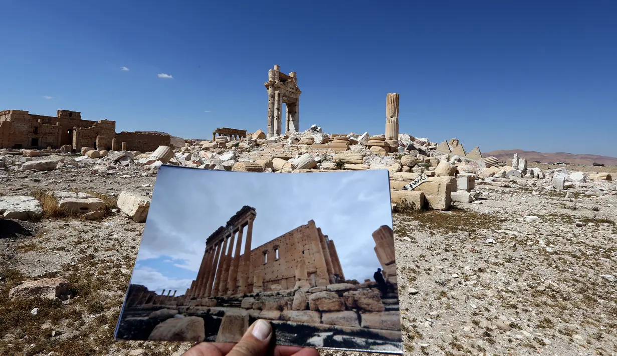 Fotografer bernama Joseph Eid memegang foto Temple of Bel yang diambil pada tanggal 14 Maret 2014 di depan sisa-sisa kuil bersejarah setelah dihancurkan oleh ISIS pada September 2015 di kota kuno Palmyra, Suriah, 31 Maret 2016. (Joseph EID/AFP)