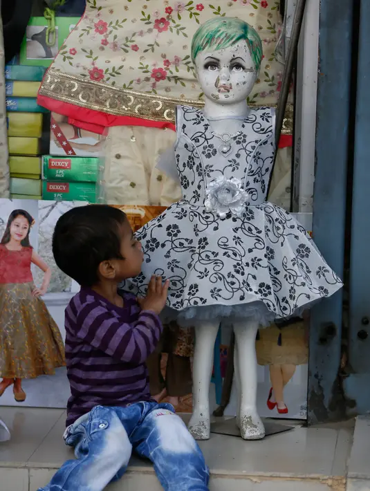 Seorang anak Muslim Kashmir menyentuh sebuah pakaian sebelum Idul Fitri di Srinagar, Kashmir yang dikuasai India (2/6/2019). Idul Fitri, menandai berakhirnya bulan puasa Ramadan. (AP Photo/Mukhtar Khan)