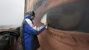 Seniman asal Italia, Jorit Agoch menyelesaikan mural yang bergambar wajah legenda sepak bola, Diego Armando Maradona di San Giovanni a Teduccio, Italia (28/2). Jorit Agoch dikenal sebagai seniman mural hyper-realistis. (AFP/Renato Esposito)
