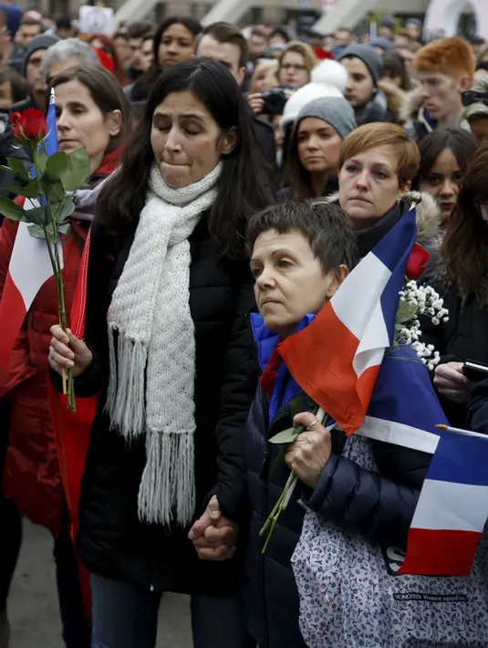 Sejumlah warga berdoa sambil membawa bendera Perancis di balai kota Toronto, Sabtu  (14/11/2015). Mereka berdoa untuk para korban yang tewas dalam peristiwa serangan di Paris. (REUTERS/Chris Helgren)