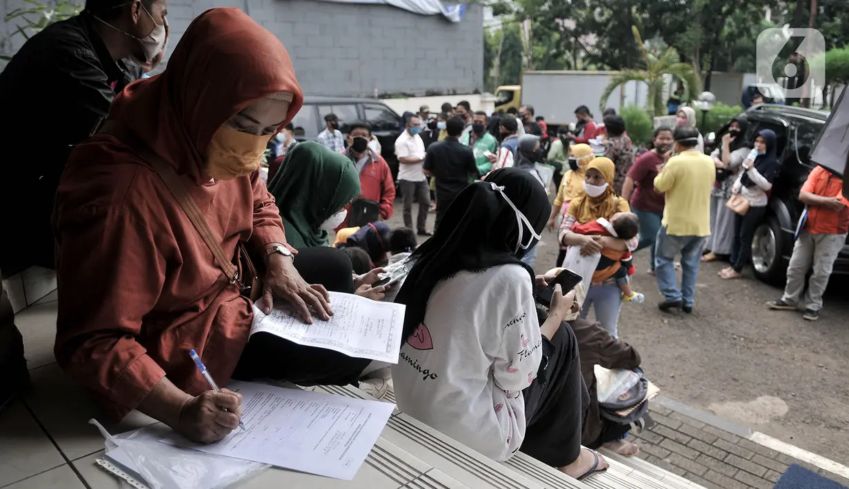 Warga mengisi data di luar gedung Kantor Suku Dinas Dukcapil Jakarta Timur, Senin (15/6/2020). Layanan tatap muka Dukcapil Jakarta Timur yang kembali dibuka sejak Jumat (12/6) lalu disambut antusias warga yang ingin mengurus dokumen administrasi kependudukan. (merdeka.com/ Iqbal S Nugroho)
