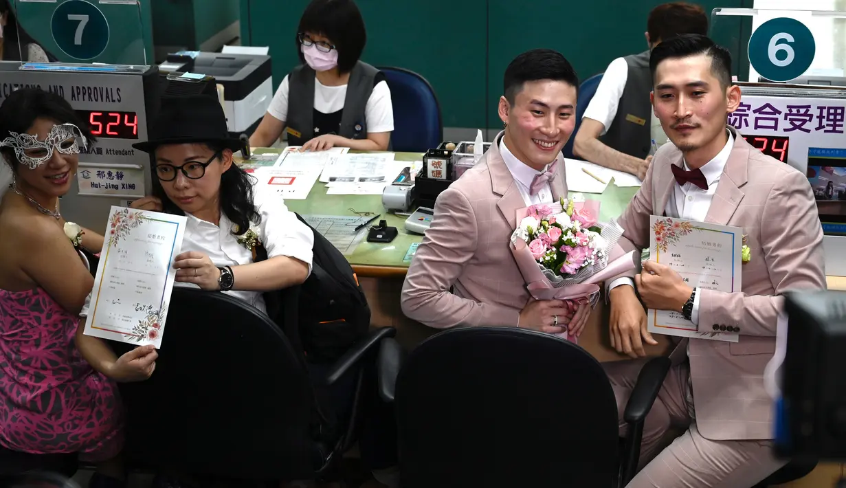 Pasangan sesama jenis Shane Lin dan Marc Yuan serta Cynical Chick dan Li Ying-Chien berpose di kantor pemerintahan Taipei, Taiwan, Jumat (24/5/2019). Ratusan pasangan sesama jenis di Taiwan bergegas ke kantor pemerintahan pada hari pertama pelegalan pernikahan sesama jenis. (Sam YEH/AFP)