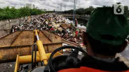 Petugas PPSU menggunakan alat berat mengumpulkan sampah sisa banjir di sepanjang Kali Cengkareng, Jakarta Barat, Kamis (9/1/2020). Tumpukan sampah di sepanjang bantaran kali dan rumah-rumah warga terlihat setelah banjir yang melanda sejumlah kawasan Jakarta mulai surut. (Liputan6.com/Johan Tallo)