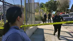 Warga melihat polisi menutup akses jalan menuju lokasi penembakan di sekolah menengah Salvador Castro, Los Angeles, Kamis (1/2). Lima orang terluka, satu di antaranya siswa berusia 15 tahun kritis karena tertembak bagian kepalanya. (AP/Damian Dovarganes)