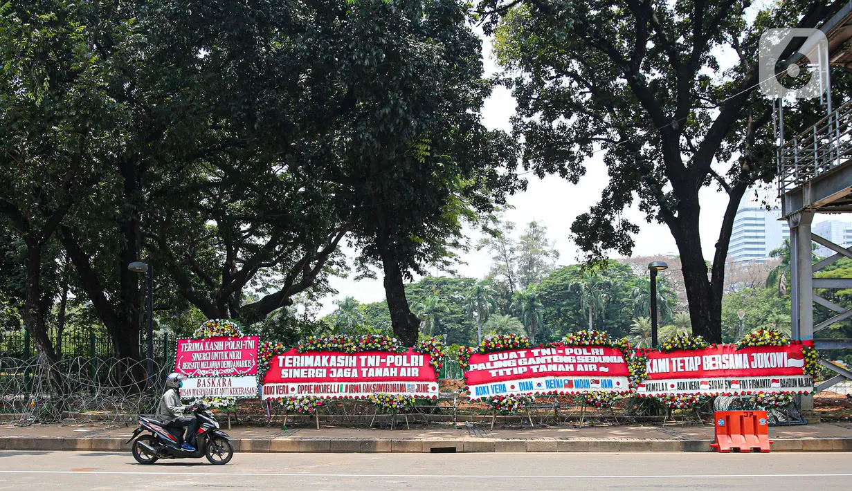 Kendaraan melintasi karangan bunga yang menghiasi kawasan Patung Kuda, Jakarta, Kamis (15/10/2020). Karangan bunga tersebut merupakan apresiasi masyarakat kepada TNI-Polri yang telah menjaga keamanan saat demo. (Liputan6.com/Faizal Fanani)