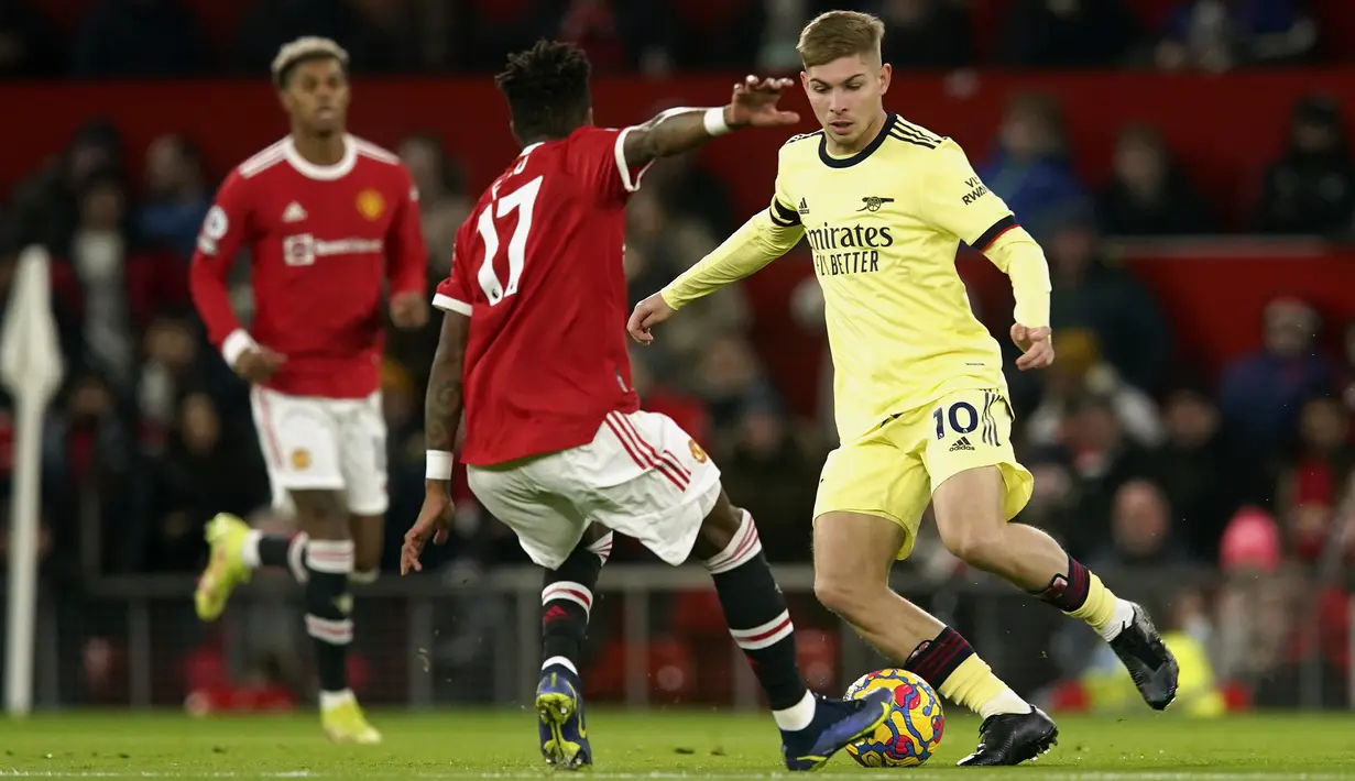 Gelandang Arsenal Emile Smith Rowe berebut bola dengan gelandang Manchester United (MU) Fred pada pekan ke-14 Liga Inggris di Old Trafford, Jumat (3/11/2021) dini hari WIB. Dua gol Cristiano Ronaldo membawa MU menang dramatis 3-2 saat menjamu Arsenal. (AP Photo/Dave Thompson)
