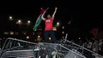 Seorang mahasiswa Universitas George Washington melambaikan bendera Palestina saat berdiri di atas barikade polisi yang diterobos untuk menduduki University Yard dalam aksi protes pro-Palestina di Washington, Minggu, 28 April 2024. (AP Photo/Cliff Owen)
