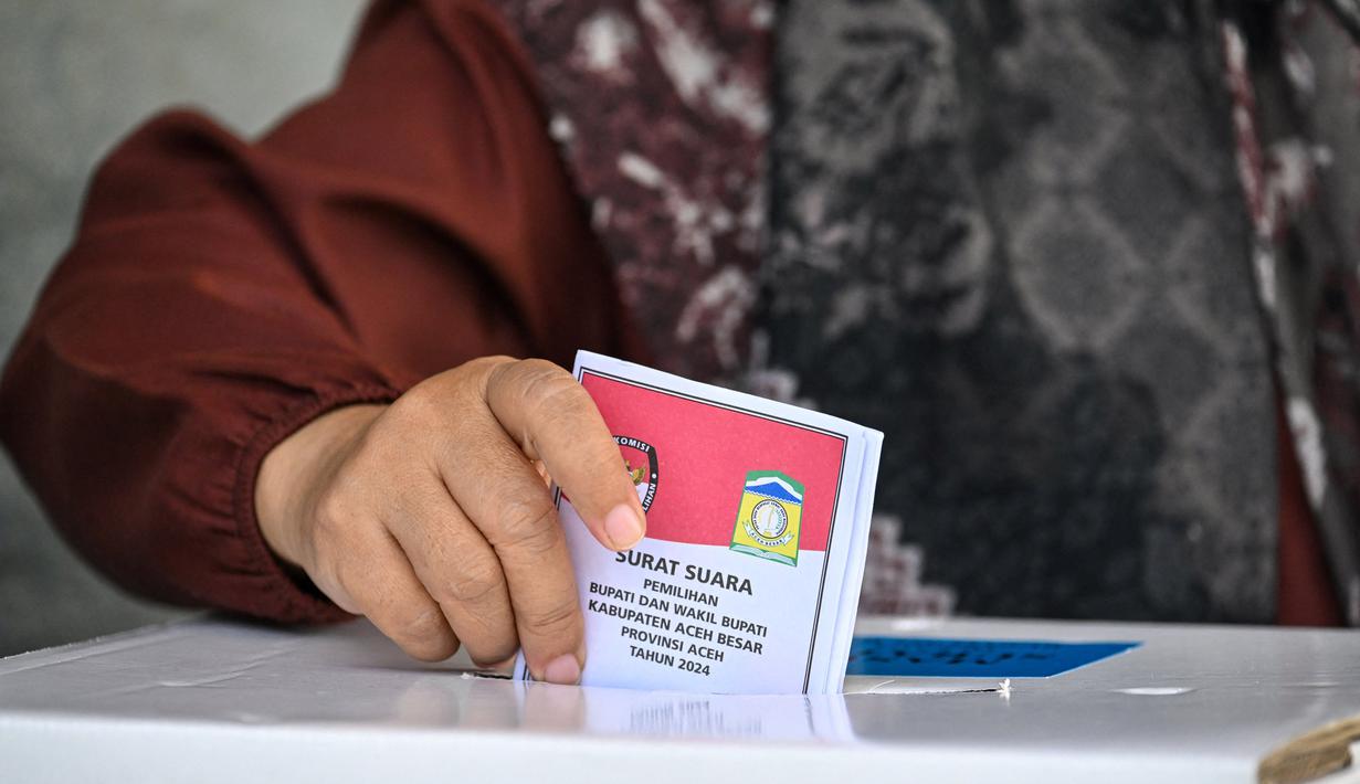 Sejak pertama kali diperkenalkan, Pilkada telah menjadi sarana untuk memilih pemimpin daerah yang diharapkan berkualitas. Tampak dalam foto, pemilih memasukkan surat suaranya dalam pemilihan kepala daerah di Darul Imarah, pinggiran Banda Aceh pada 27 November 2024. (CHAIDEER MAHYUDDIN/AFP)
