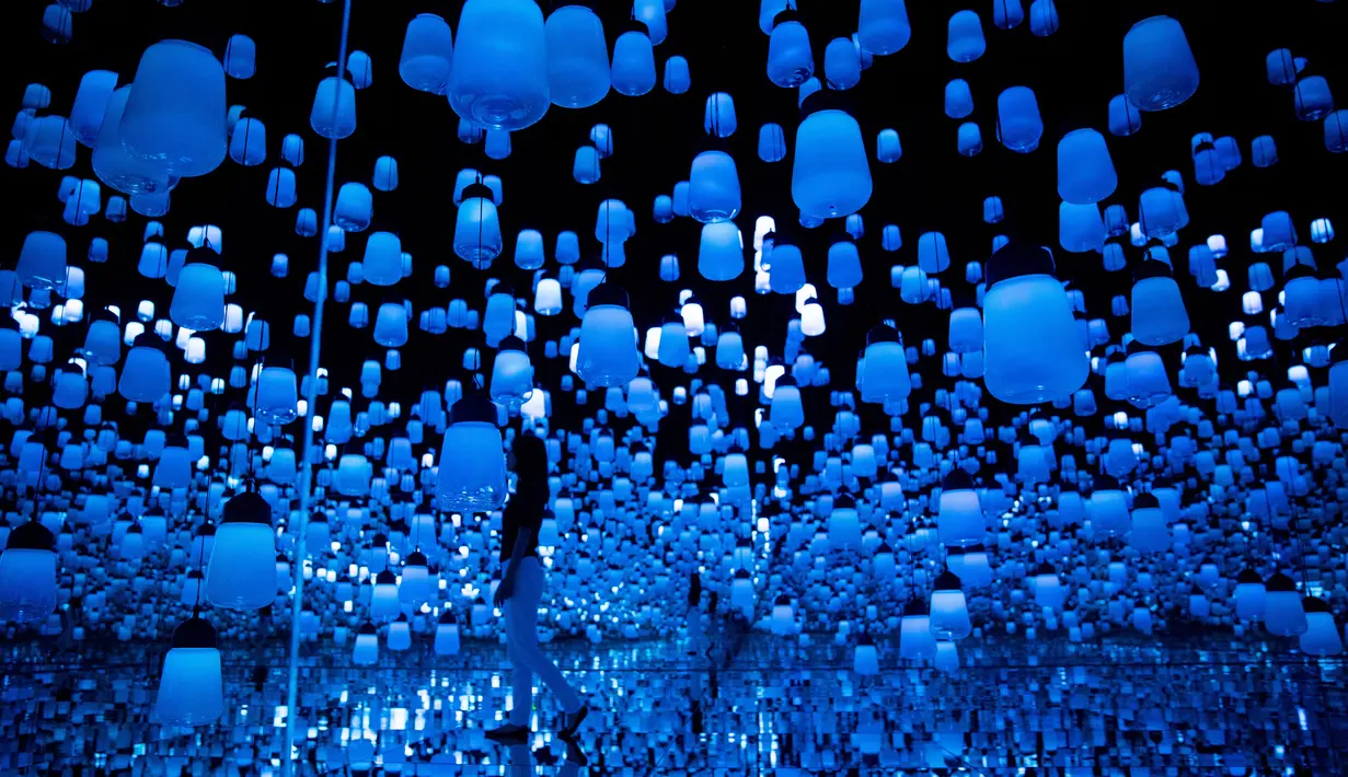 Seorang wanita berjalan di ruangan yang penuh instalasi lampu gantung di Mori Building Digital Museum Seni, Tokyo, Jepang (1/5). Tokyo menggelar pameran seni digital yang menggabungkan proyeksi gambar dan suara. (AFP Photo/Behrouz Mehri)