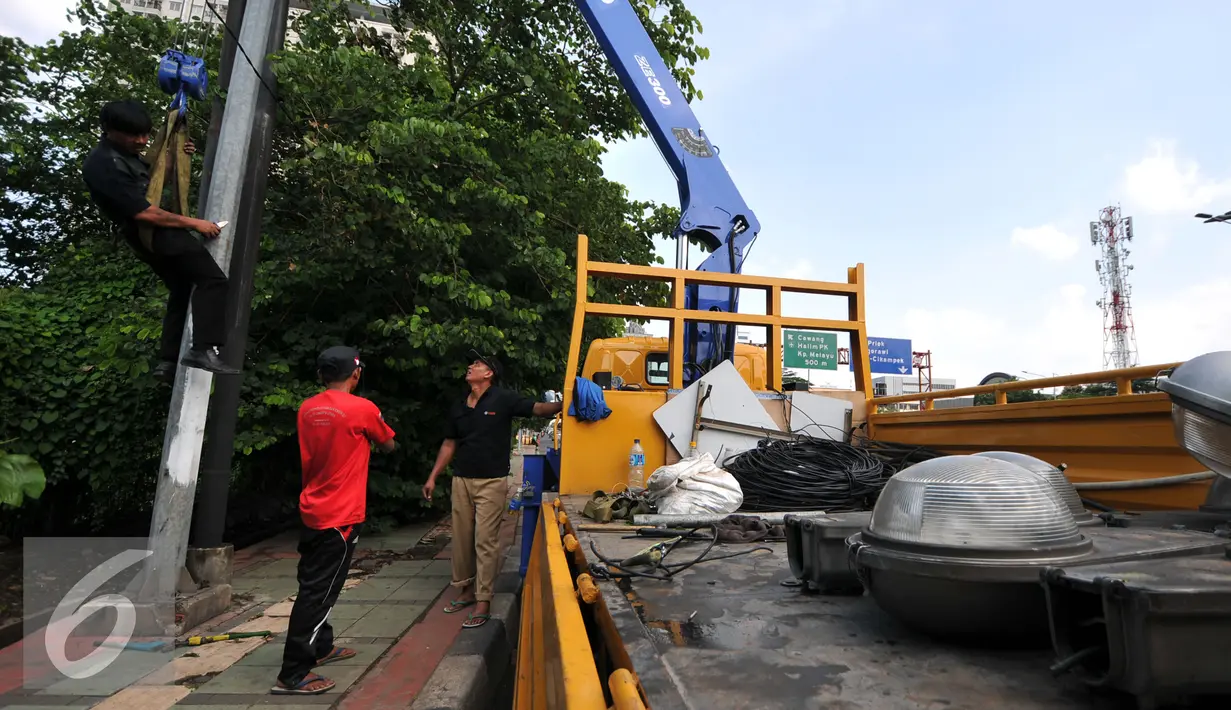 Pekerja usai mencopot lampu dan mengganti tiang lampu PJU di Jakarta, Selasa (29/12). Pemrov DKI Jakarta akan mengganti seluruh lampu listrik Penerangan Jalan Umum (PJU) dari konvensional menjadi lampu hemat energi LED. (Liputan6.com/Yoppy Renato)